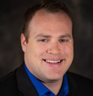 Picture of Brent Reed smiling in front of dark background